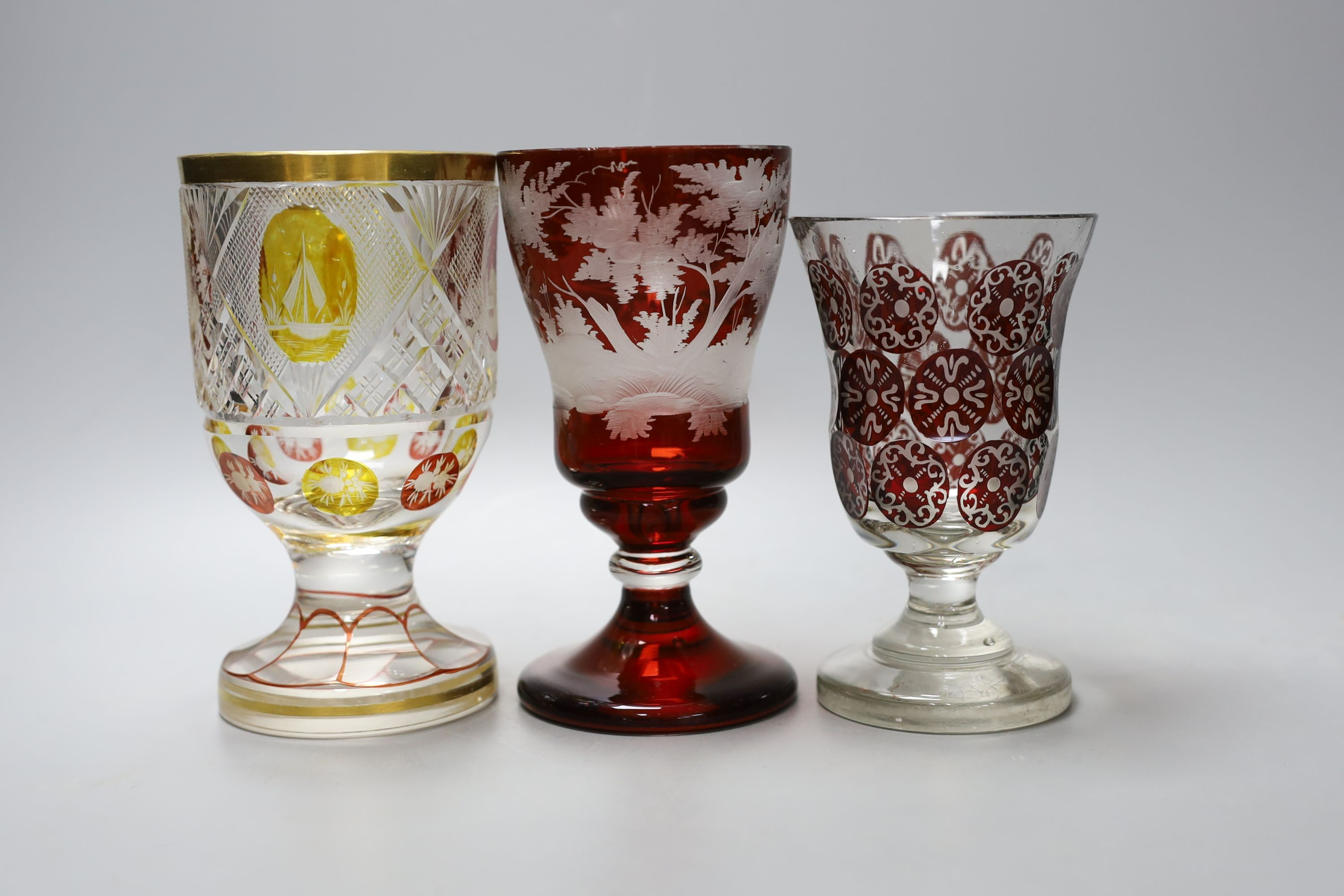 Three Bohemian wheel engraved ruby glass goblets, tallest 16.5cm